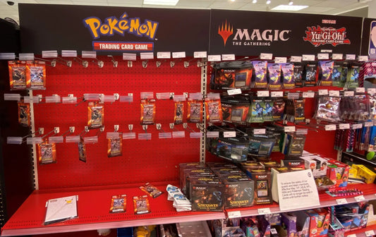 Store display shelf with Pokémon, Magic: The Gathering, and Yu-Gi-Oh! trading cards.